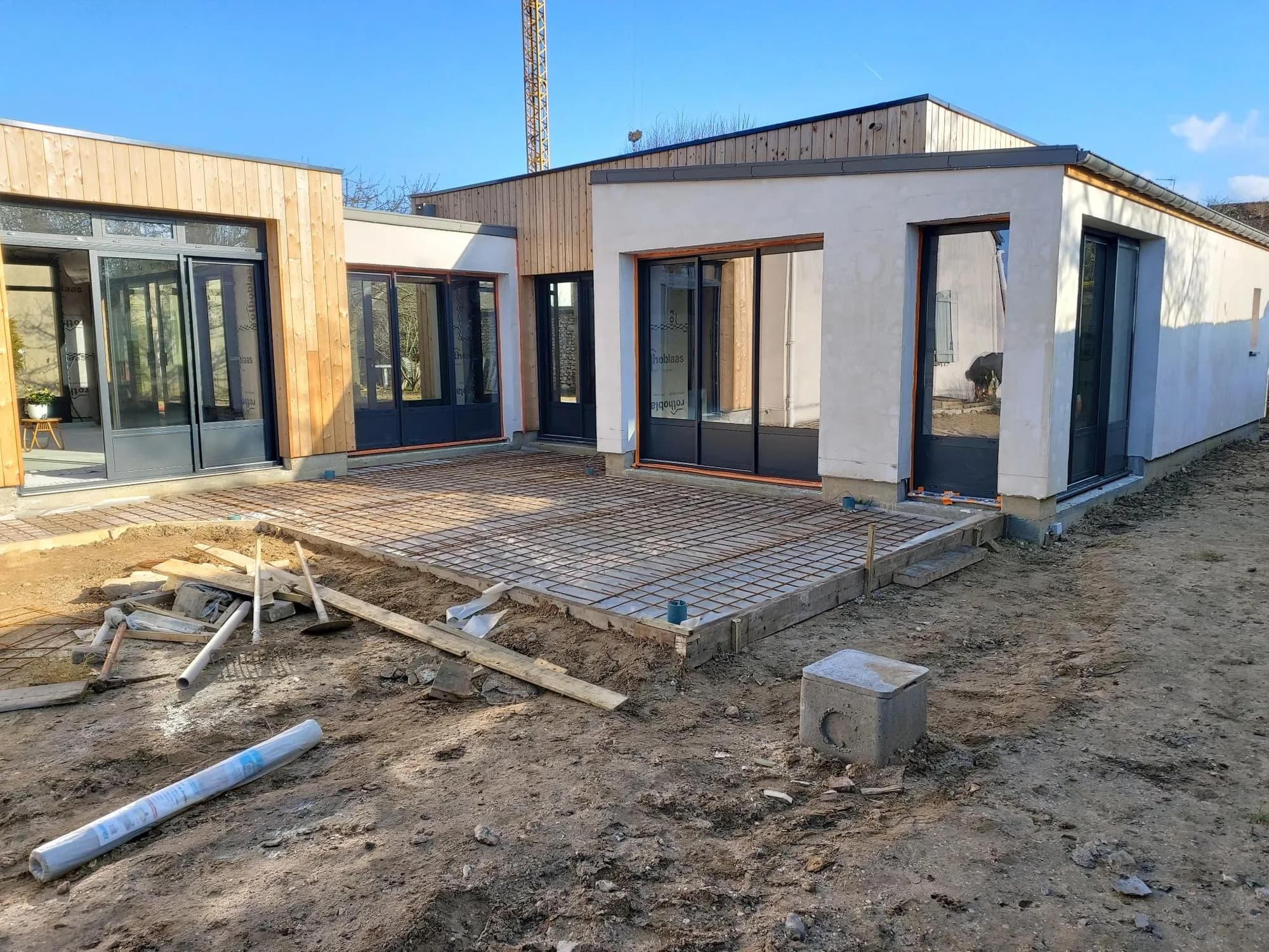 Extension contemporaine en cours de finition avec dalle de terrasse et menuiseries noires