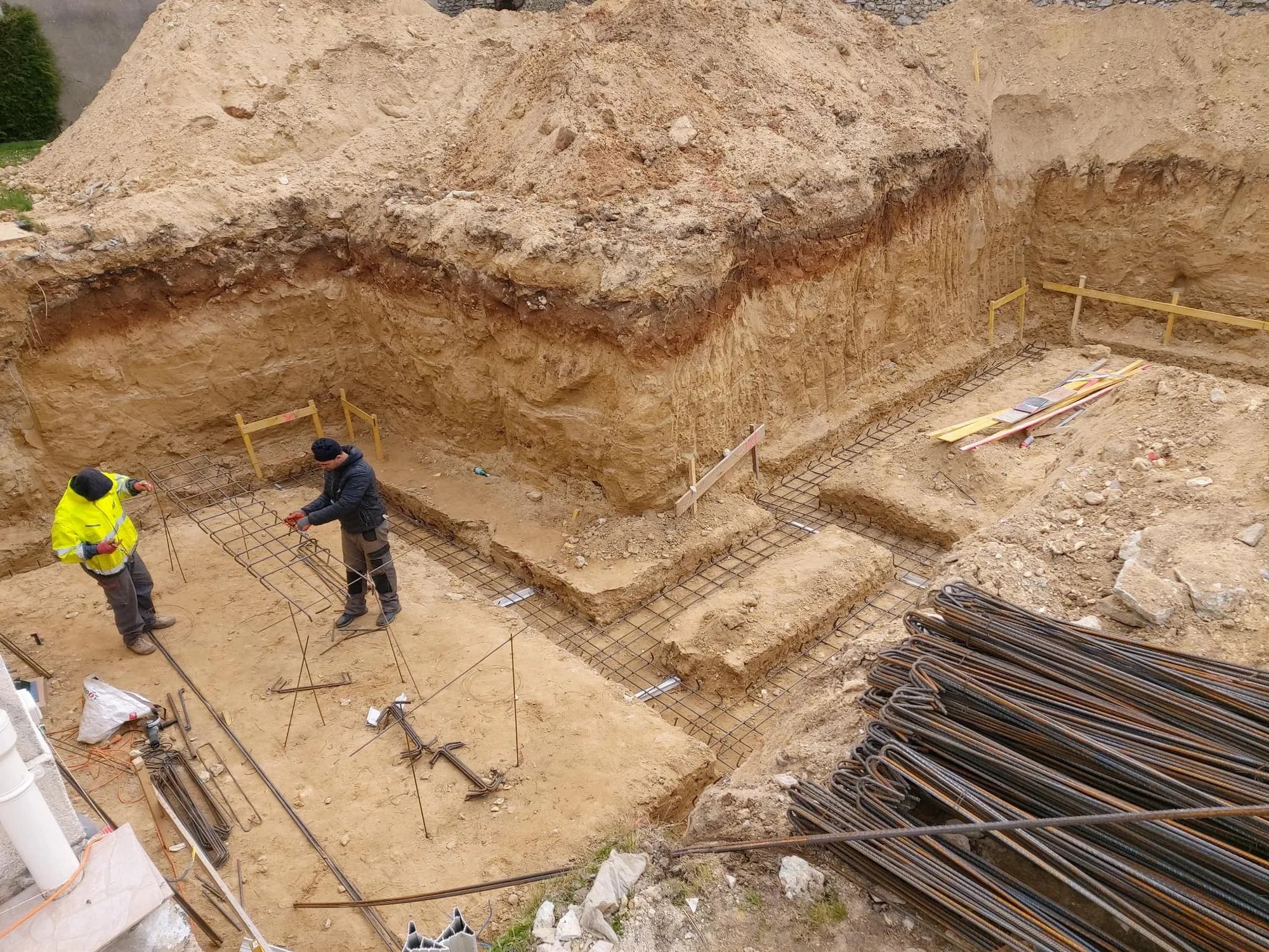 Deux compagnons ferraillent les semelles de fondation d'une maison sur un chantier