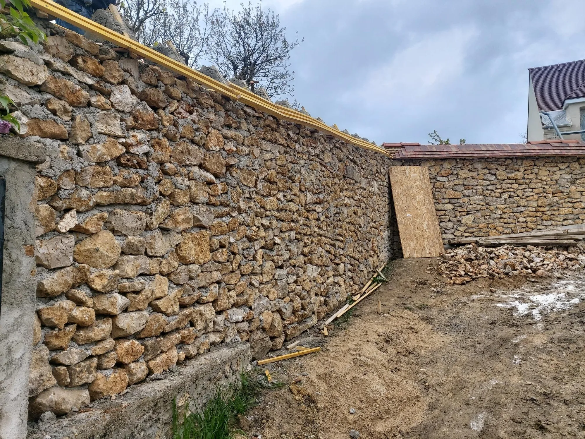Long mur de clôture en pierre restauré et rejointoyé