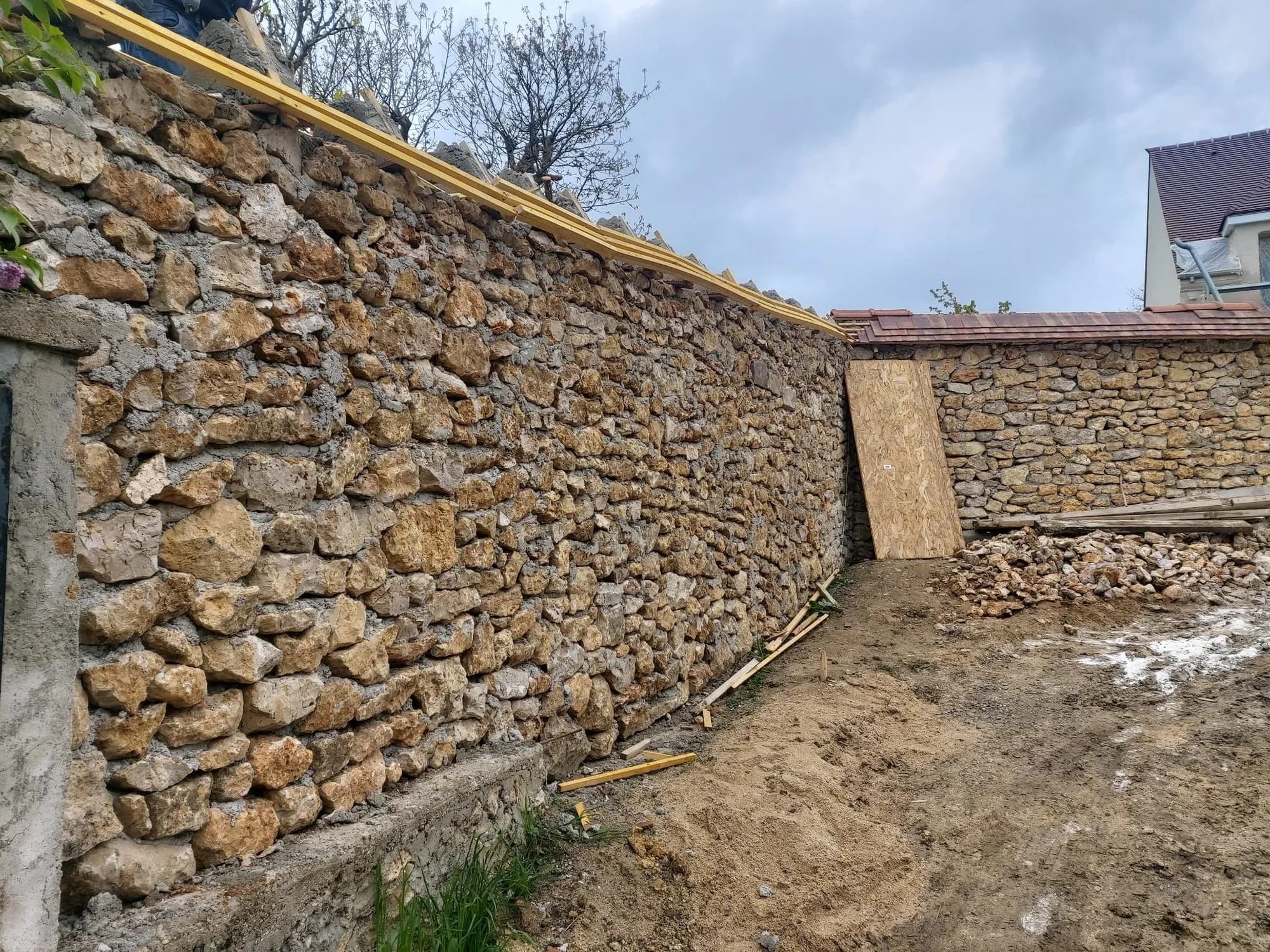 Long mur de clôture en pierre restauré et rejointoyé