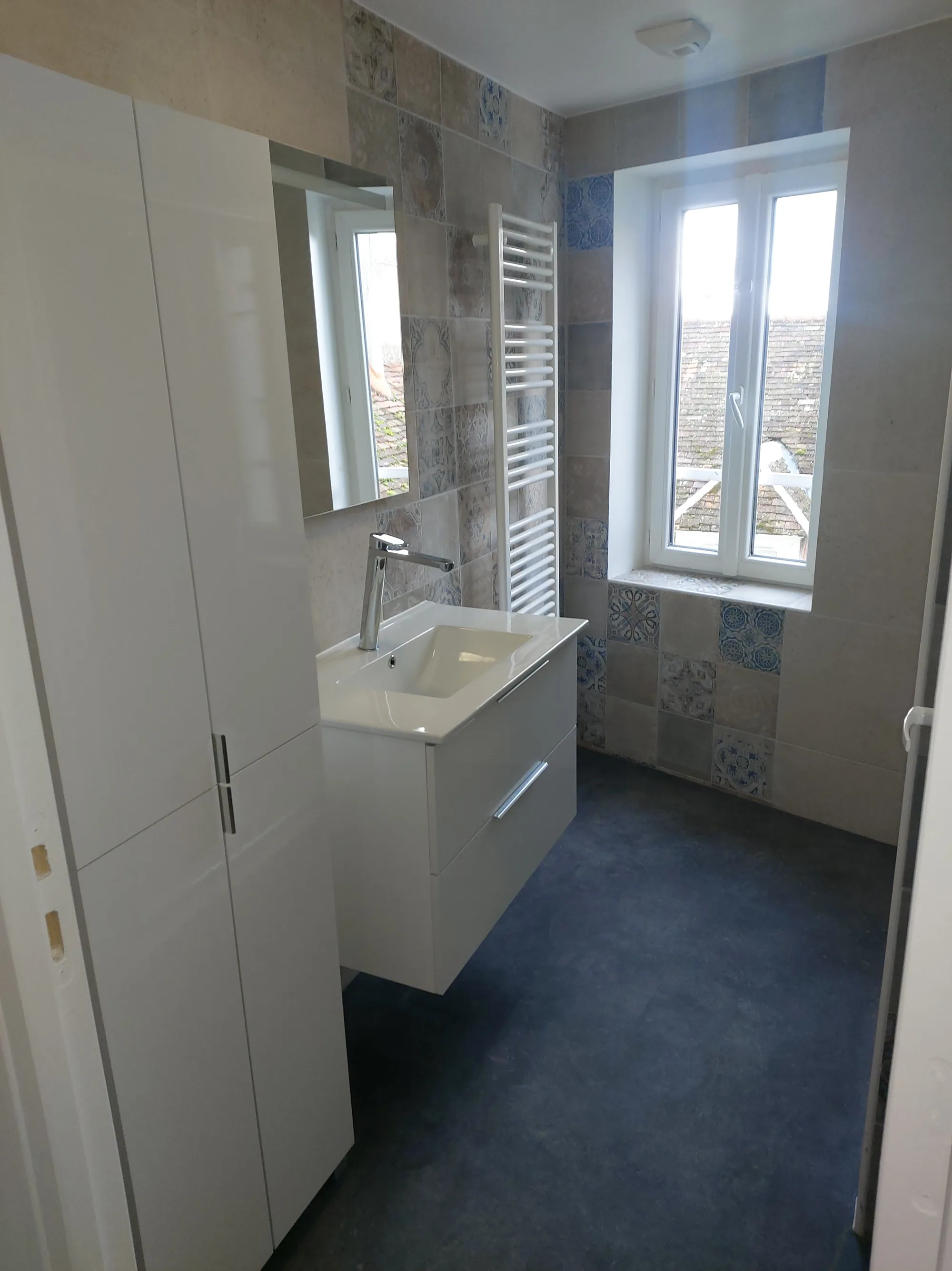 Salle de bain rénovée avec meuble vasque suspendu blanc et carrelage à motifs